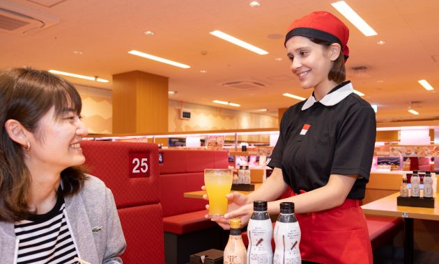 ホールでソフトドリンクをお客様に提供しているスタッフの写真