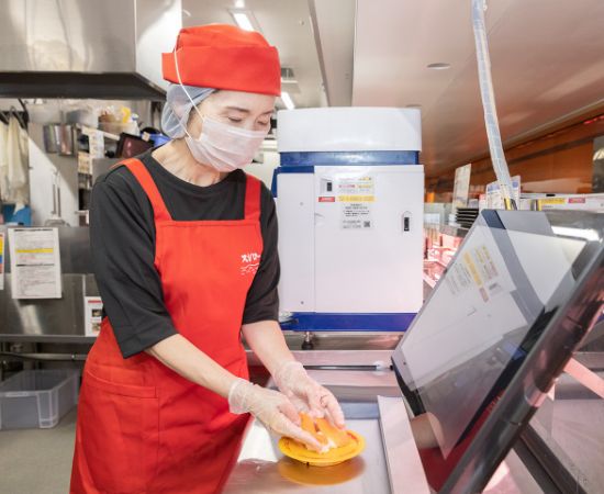 キッチンでお寿司をお皿に盛り付けているスタッフの写真